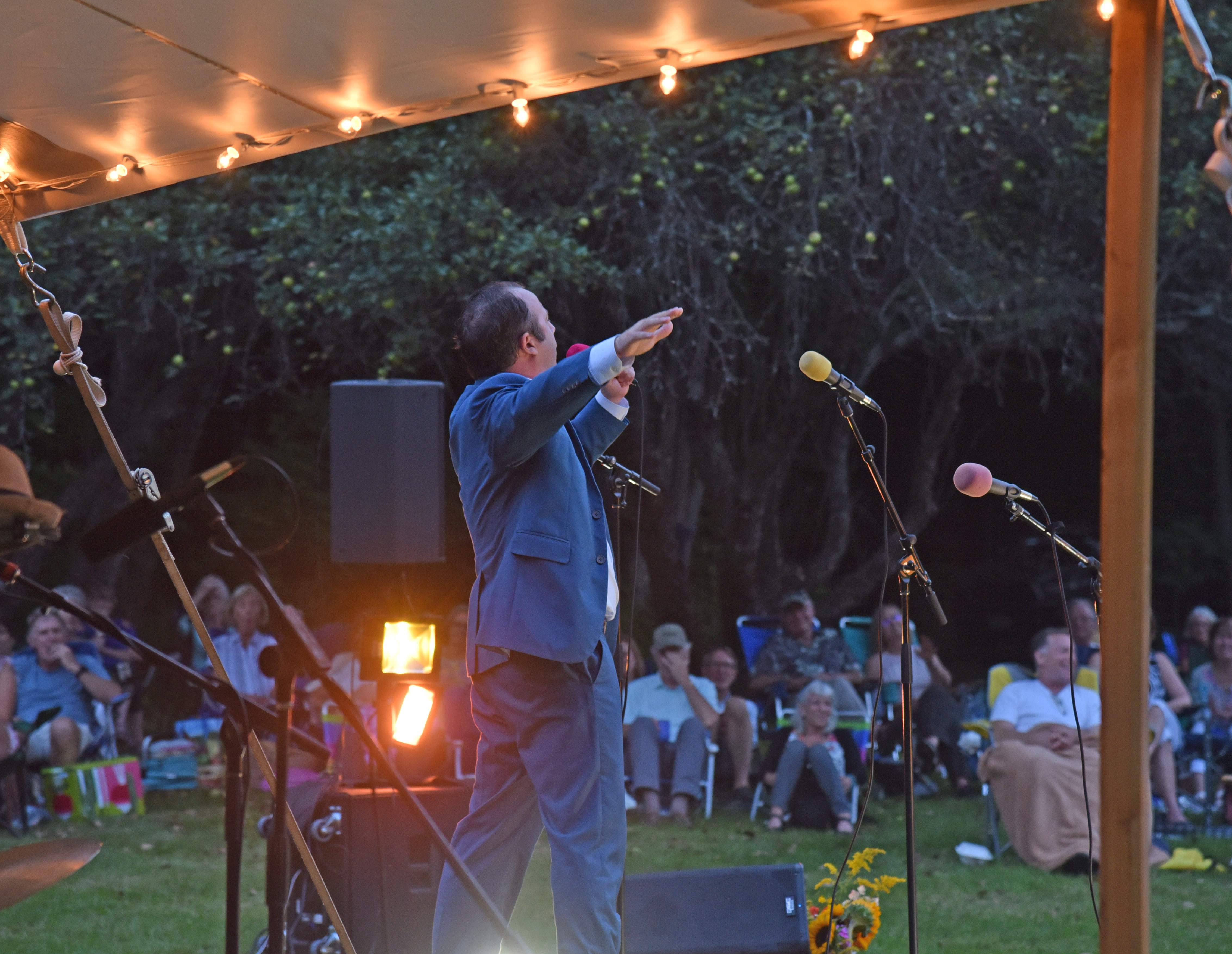 Broadway star Merritt David Janes performing outdoors under a lighted tent with the audience seated on the lawn at Moose Meadow.